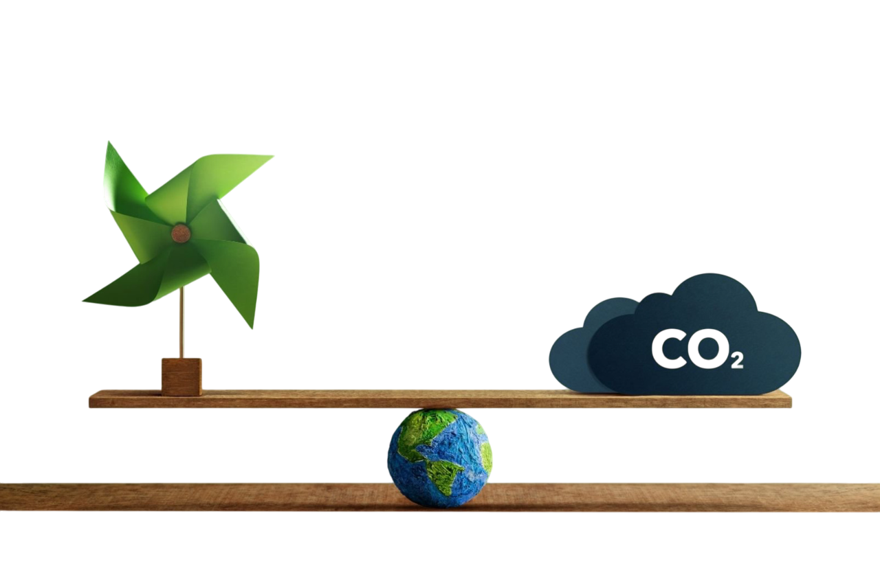 A green pinwheel and a dark cloud labeled "CO2" balance on a wooden plank above a small Earth sculpture. The image conveys environmental themes.